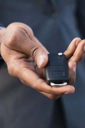 Car rental concept. Man holding car key in hand, stretching to camera